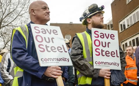 Workers stand with signs at Tata steel works - Credit: WPA Pool/Getty Images