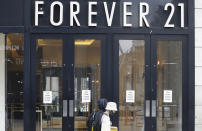 People walk past a branch of Forever 21, in London, Thursday, July 16, 2020. Unemployment across the U.K. has held steady during the coronavirus lockdown as a result of a government salary support scheme, but there are clear signals emerging that job losses will skyrocket over coming months. The Office for National Statistics said Thursday there were 649,000 fewer people, or 2.2%, on payroll in June when compared with March when the lockdown restrictions were imposed. (AP Photo/Alastair Grant)