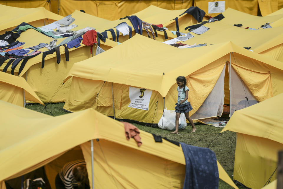 A girl walks in a camp built by the municipal government for homeless Venezuelan migrants in Bogota, Colombia, Wednesday, Nov. 21, 2018. The camp was built by the city's social welfare secretary to accommodate migrants who had previously been living in tents made of plastic sheets and scrap materials outside the city's bus terminal. (AP Photo/Ivan Valencia)