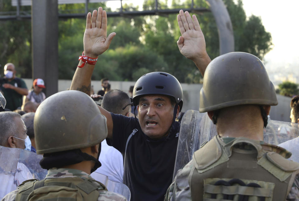 An anti-government protester reacts in front of Lebanese soldiers, during a protest against the Lebanese President Michel Aoun near the presidential palace, in Baabda east of Beirut, Lebanon, Saturday, Sept. 12, 2020. Lebanese soldiers fired rubber bullets and live rounds in the air to disperse hundreds of protesters trying to march to the presidential palace during an anti-government demonstration. (AP Photo/Bilal Hussein)