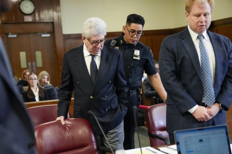 Rare-book dealer Glenn Horowitz, center is seated in the defendants chair in the supreme court, Wednesday, Feb. 21, 2024, in New York. A criminal case involving handwritten lyrics to the classic rock megahit “Hotel California” and other Eagles favorites went to trial Wednesday in New York, with three men accused of scheming to thwart band co-founder Don Henley’s efforts to reclaim the allegedly ill-gotten documents. (AP Photo/Mary Altaffer)