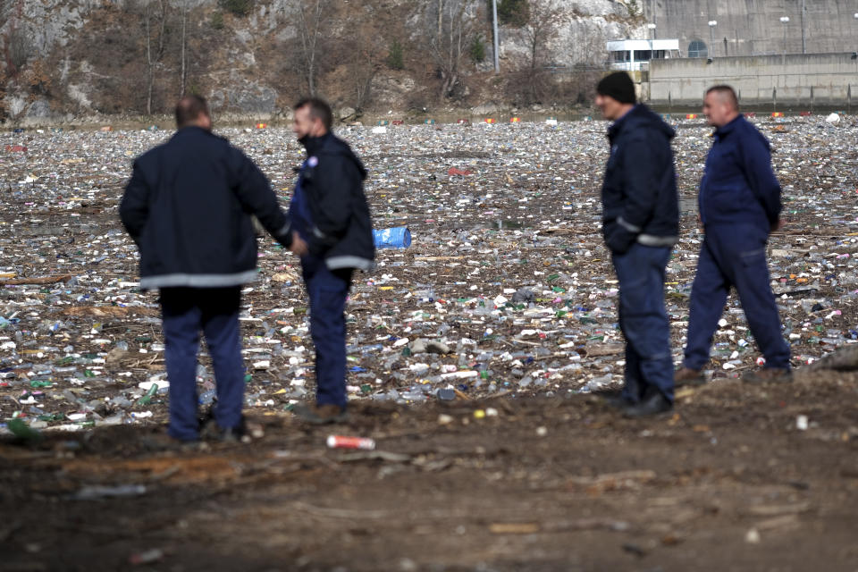 Workers look at garbage floating in the Drina river near Visegrad, eastern Bosnia, Wednesday, Feb. 24, 2021. Environmental activists in Bosnia are warning that tons of garbage floating down the Balkan country's rivers are endangering the local ecosystem and people's health. The Drina River has been covered for weeks with trash that has piled up faster than the authorities can clear it out. (AP Photo/Kemal Softic)