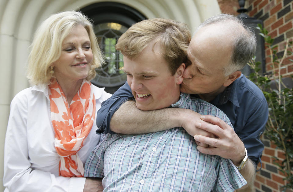 In this photo made Saturday, April 1, 2017, Clay Heighten, right, and Debra Caudy, left, embrace their autistic 19-year-old son Jon Heighten as they pose for a photo at their home in the Dallas area town of University Park, Texas. Jon Heighten's parents are helping lead a 29-acre housing development and community for autistic adults that will break ground in the coming months. (AP Photo/LM Otero)