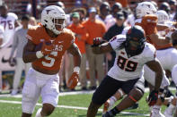 Texas running back Bijan Robinson (5) runs past Oklahoma State defensive end Tyler Lacy (89) during the first half of an NCAA college football game in Austin, Texas, Saturday, Oct. 16, 2021. (AP Photo/Chuck Burton)