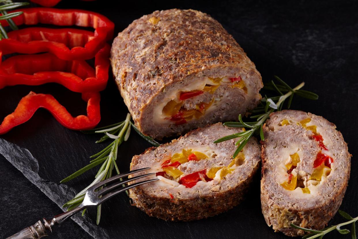 Closeup of minced meat loaf with red and yellow pepper and cheese.