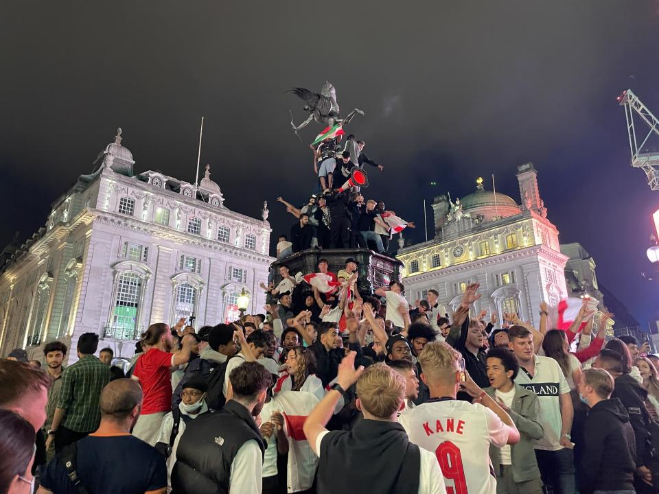 England football fans climb the statue of Eros in Piccadilly Circus, central London, after England beat Ukraine 4-0 in their Euro2020 quarter final match. Picture date: Saturday July 3, 2021.