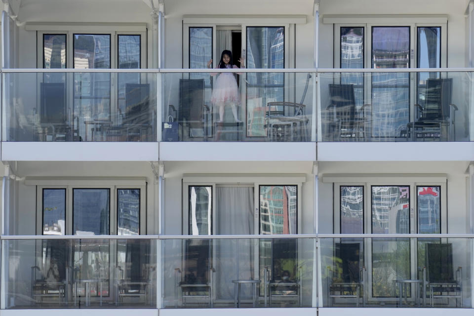 A passenger waves from the Spectrum of the Seas cruise ship docked at Kai Tak cruise terminal in Hong Kong Wednesday, Jan. 5, 2022. Thousands of passengers were being held Wednesday on the cruise ship in Hong Kong for coronavirus testing after health authorities said nine passengers were linked to a recent omicron cluster and ordered the ship to turn back. (AP Photo/Vincent Yu)