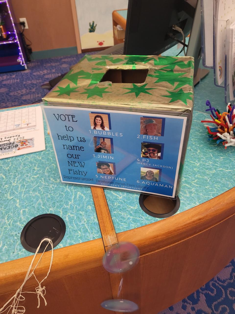 A ballot box displays photos of the librarians who suggested each possible name for the beta fish. Library visitors cast the most votes for Bubbles.