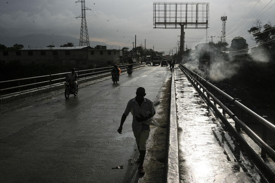 People cross the Marassa Fleuriot bridge in Croix-des-Bouquets, near Port-au-Prince, Haiti, Tuesday, Oct. 19, 2021. A general strike continues in Haiti demanding that authorities address the nation’s lack of security, four days after 17 members of a U.S.-based missionary group were abducted by a gang. (AP Photo/Matias Delacroix)