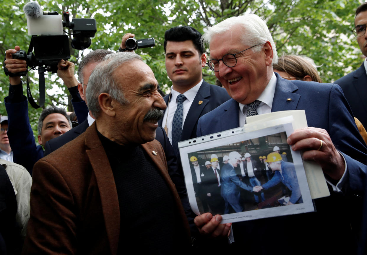 Bundespräsident Frank-Walter Steinmeier (rechts) mit einem ehemaligen Fabrikarbeiter, der ihm ein gemeinsames Foto aus früheren Tagen zeigt (Bild: REUTERS/Dilara Senkaya)
