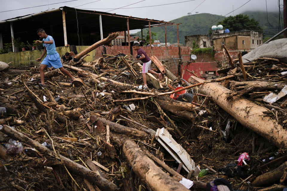 A boy carries sneakers he found amidst the rubble caused by flooding in Las Tejerias, Venezuela, Sunday, Oct. 9, 2022. At least two people died after days of heavy rain caused flash flooding and the overflow of a ravine. (AP Photo/Matias Delacroix)