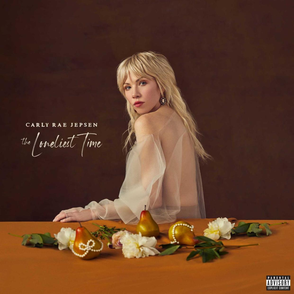 carly rae jepsen stands near a table with fake fruit and flowers