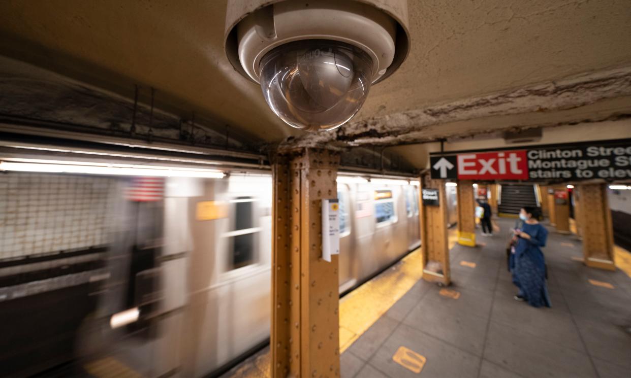 A video surveillance camera is installed on the ceiling above a subway platform in New York City.