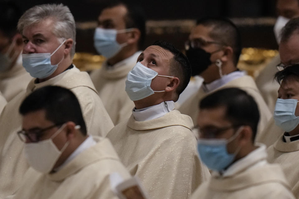 Priests wait for Pope Francis to celebrate Christmas Eve Mass, at St. Peter's Basilica at the Vatican, Friday Dec. 24, 2021. (AP Photo/Alessandra Tarantino)