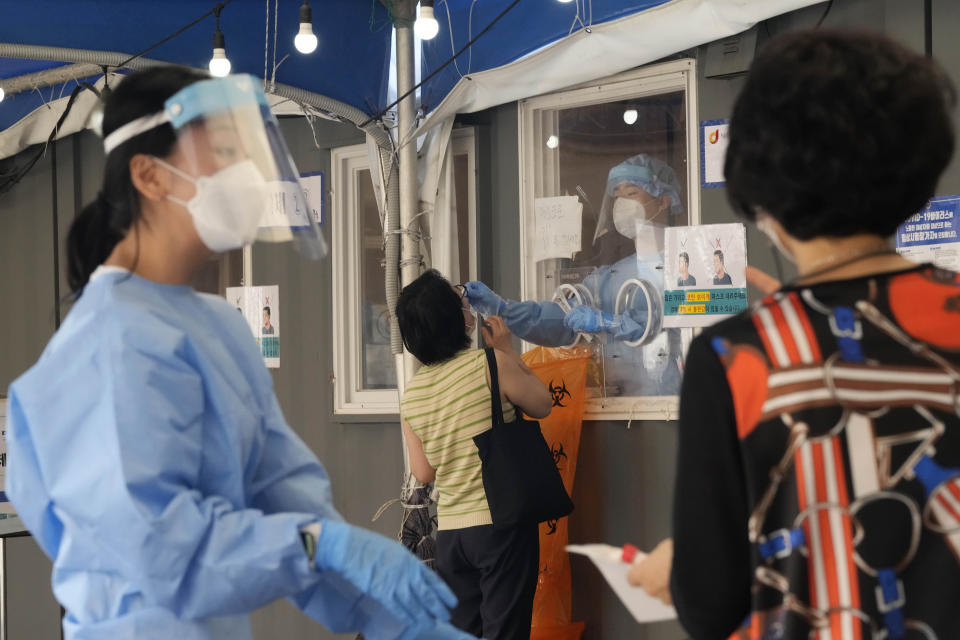 A medical worker in a booth takes a nasal sample from a woman during coronavirus testing at a makeshift testing site in Seoul, Wednesday, July 28, 2021. South Korea reported a new daily high for coronavirus cases, a day after authorities enforced stringent restrictions in areas outside the capital region. (AP Photo/Ahn Young-joon)