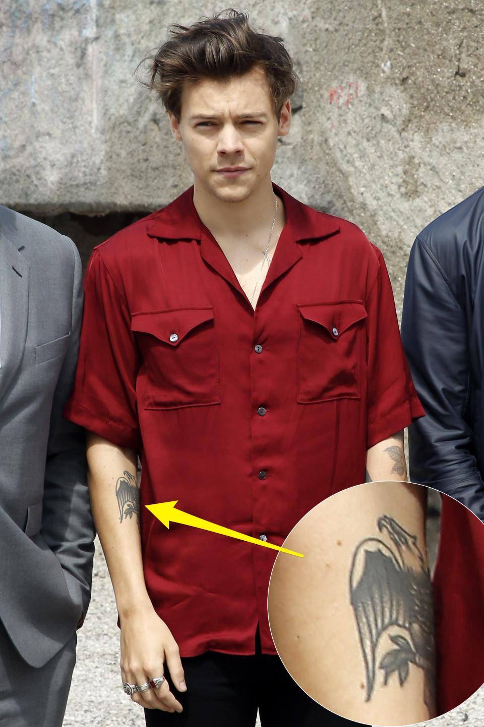 A yellow arrow pointing to Harry Styles' eagle tattoo on his right arm.