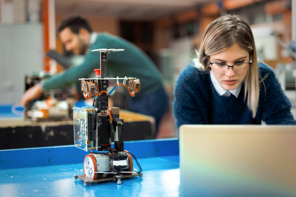 Young attractive woman engineer working on robotics project using laptop