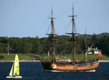 A small sailing boat sails past the replica of the famous 18th century ship The Endeavour as it sits anchored in Botany Bay, Australia April 17, 2005. REUTERS/David Gray/File Photo