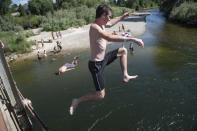 Patrons of the Bitterroot River jump into the cool water as temperatures crested 100 degrees in Missoula, Montana, on Wednesday, June 30, 2021. (AP Photo/Tommy Martino)