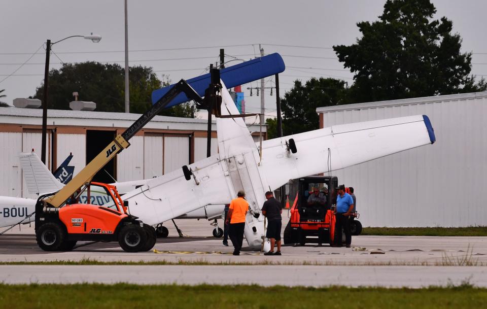 A crew tends to a flipped-over plane Friday morning on the north side of Merritt Island Airport. Three planes flipped over amid high winds about 11:15 p.m. Thursday, the National Weather Service reported.