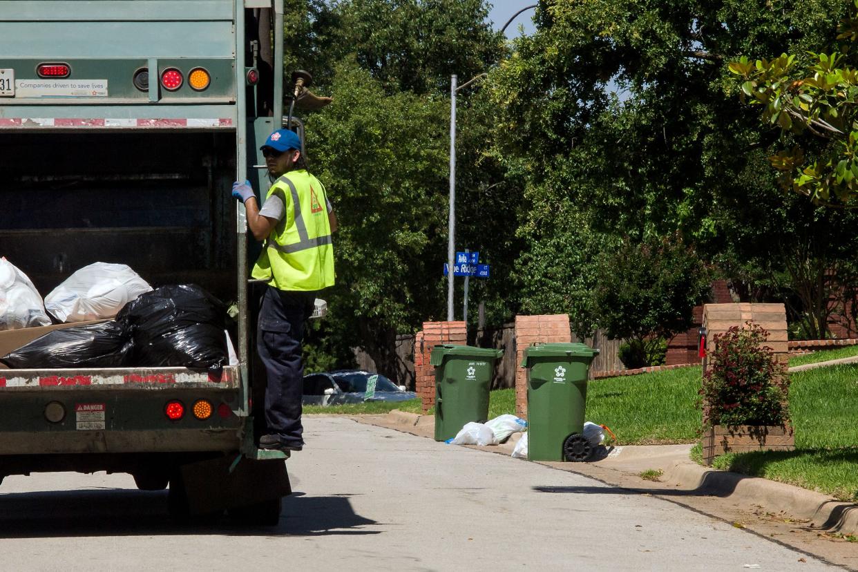 garbage truck with sanitation worker in suburbian neighborhood