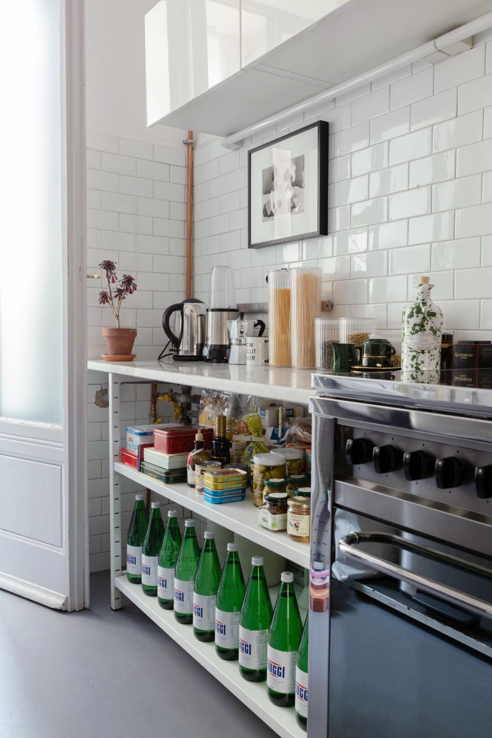 The apartment came equipped with a gas stove by Lofra and white industrial shelving topped by a marble worktop.