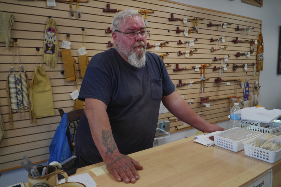Travis Erickson stands in his shop where he sells Indigenous native art, including hand carved pipes made of a unique variety of quarry pipestone called catlinite, on Wednesday, May 3, 2023, in Pipestone, Minn. “Sacredness is going to be defined by you — that’s between you and the Creator,” says Erickson, a fourth-generation carver who’s worked pipestone in the area for more than two decades and embraces a less restrictive view. “Everything on this Earth is spiritual.” (AP Photo/Jessie Wardarski)