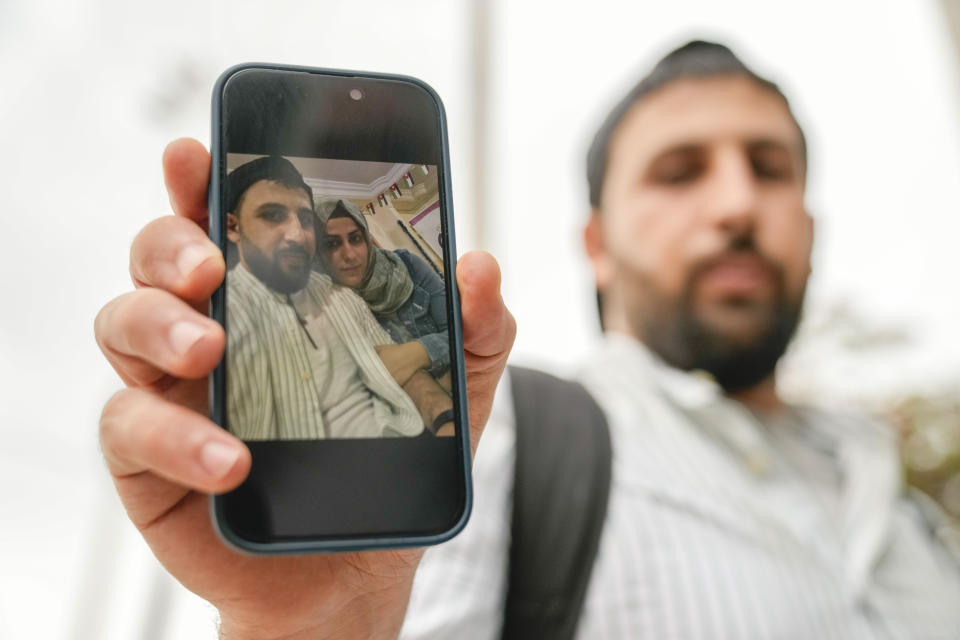 Kassem Abo Zeed holds up a photograph with his wife, Ezra, who is missing after a fishing boat carrying migrants sank off southern Greece, in the southern port city of Kalamata, Thursday, June 15, 2023. Abo Zeed traveled from Hamburg, Germany, to try and find his wife and her missing brother, Abdullah Aoun. (AP Photo/Thanassis Stavrakis)