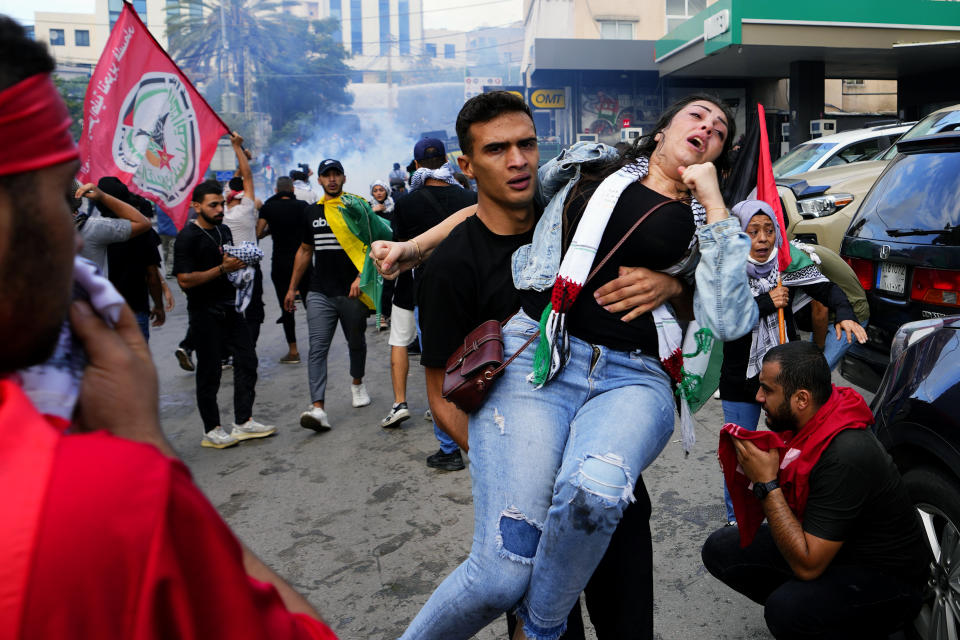 A protester carries an injured woman during a demonstration in solidarity with the Palestinian people in Gaza, near the U.S. embassy in Aukar, a northern suburb of Beirut, Lebanon, Wednesday, Oct. 18, 2023. (AP Photo/Hassan Ammar)