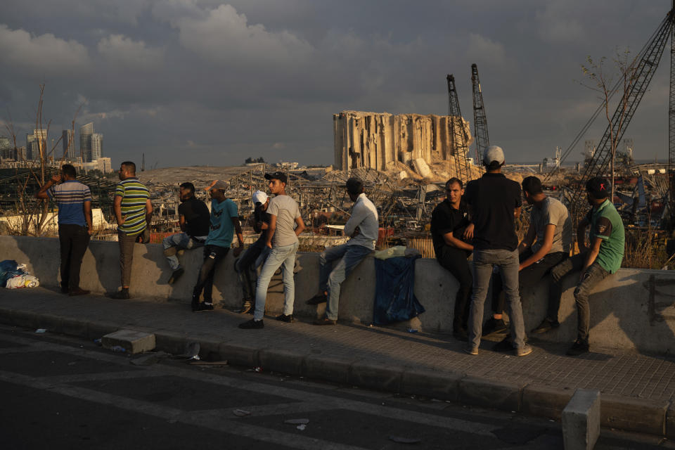 People sit near the site of last week's explosion that hit the seaport of Beirut, Lebanon, Tuesday, Aug. 11, 2020. The massive explosion is just the latest in multiple crises that have hit Lebanon the past year, including massive protests, economic collapse and the coronavirus pandemic. Some Lebanese, whether poor or middle class, now feel their resolve is simply broken. (AP Photo/Felipe Dana)