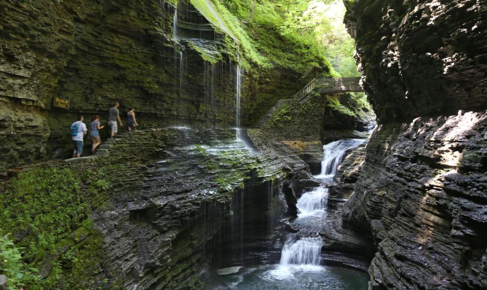 Visitors walk along the Gorge Trail and pass underneath the iconic Rainbow Falls at Watkins Glen State Park in Watkins Glen. The falls is one of two that visitors can walk underneath.