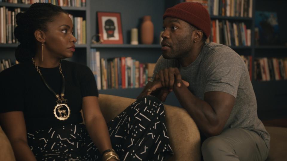 Yahya Abdul-Mateen II and Teyonah Parris sit together on a couch in Candyman film