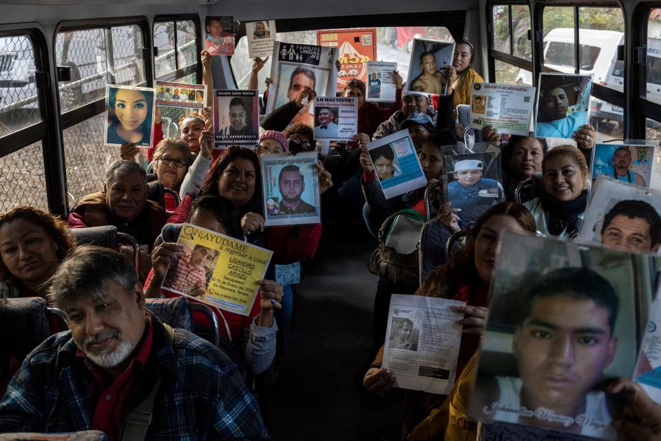 Members of the VII National Search Brigade for Disappeared Persons, in a bus to take them to the search site, show pictures of their family members who are missing.