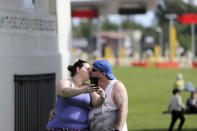 In this photo taken May 17, 2020, a couple takes a selfie as they kiss under the Peace Arch at the border between the U.S. and Canada at Peace Arch Park in Blaine, Wash. With the border closed to nonessential travel amid the global pandemic, families and couples across the continent have found themselves cut off from loved ones on the other side. But the recent reopening of Peace Arch Park, which spans from Blaine into Surrey, British Columbia, at the far western end of the 3,987-mile contiguous border, has given at least a few separated parents, siblings, lovers and friends a rare chance for some better-than-Skype visits. (AP Photo/Elaine Thompson)