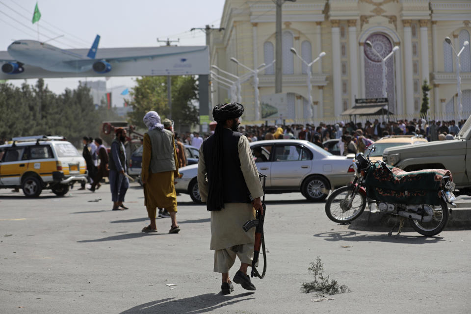 Taliban fighters stand guard in front of the Hamid Karzai International Airport, in Kabul, Afghanistan, Monday, Aug. 16, 2021. Thousands of people packed into the Afghan capital's airport on Monday, rushing the tarmac and pushing onto planes in desperate attempts to flee the country after the Taliban overthrew the Western-backed government. (AP Photo/Rahmat Gul)