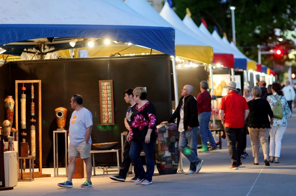 People look at artwork displayed in row of tents April 25, 2019, along Colcord Drive at the 2019 Festival of the Arts in Bicentennial Park in downtown Oklahoma City.