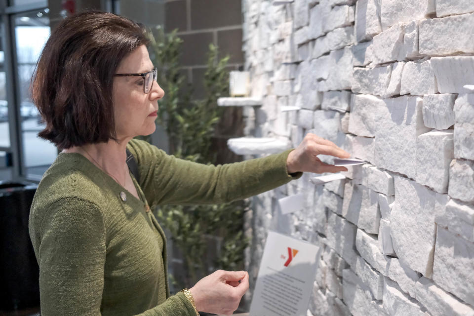 Linda Carr places a written prayer in the crevice of a new prayer wall during a recent dedication ceremony for the wall featured at the Earlywine Park YMCA in Oklahoma City.