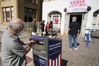 FILE - In this Oct. 19, 2020, file photo, a voter submits a ballot in an official drop box during early voting in Athens, Ga. The county officials who run elections are facing a slate of new punishments as part of a nationwide Republican campaign to roll back access to the ballot, months after many hailed them as heroes for the creative ways they expanded voting access last year during the coronavirus outbreak. (AP Photo/John Bazemore, File)