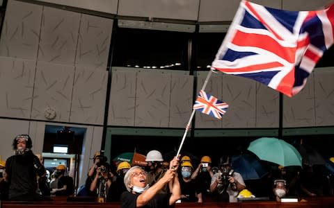 A protester waves the British Union Jack flag in the parliament chamber after they broke into the government headquarters in Hong Kong on July 1, 2019 - Credit: &nbsp;PHILIP FONG/&nbsp;AFP