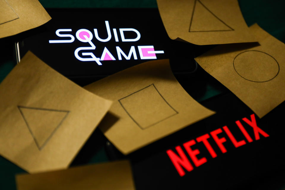 Netflix and Squid Game series logos displayed on a phone screens are seen with symbols known from the series, drawn on pieces of paper, in this illustration photo taken in Krakow, Poland on October 18, 2021. (Photo by Jakub Porzycki/NurPhoto via Getty Images)