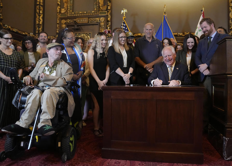 Minnesota Gov. Tim Walz, seated at right, signs a bill to legalize recreational marijuana for people over the age of 21, making Minnesota the 23rd state to do so, Tuesday, May 30, 2023, in St. Paul, Minn. (AP Photo/Abbie Parr)