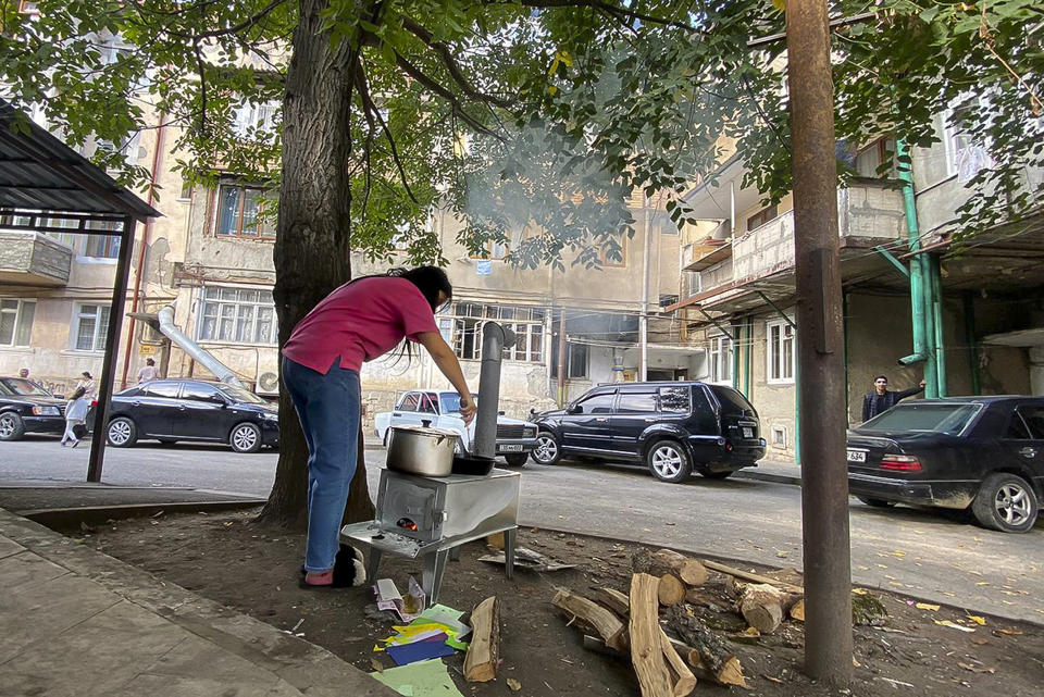 A woman cooks on makeshift stove in a yard in Stepanakert, Nagorno-Karabakh on Thursday, Sept. 21, 2023. Azerbaijan President Ilham Aliyev declared victory in a teleAuthorities in Nagorno-Karabakh accused Azerbaijan on Thursday of violating the cease-fire agreement by firing on Stepanakert, the capital of the disputed region, according to the Russian news agency Interfax. Azerbaijan's Defense Ministry denied there had been any attack, the Azerbaijan news agency reported. (AP Photo/Siranush Sargsyan)