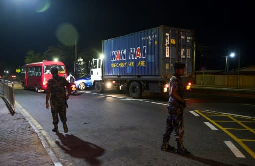 Sri Lankan security personnel stand guard at a checkpoint in Colombo after authorities imposed a nationwide night curfew