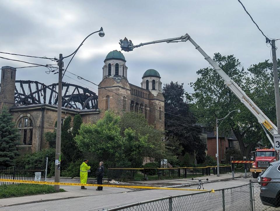 a man in neon yellow protective gear stands outside a burned-down church