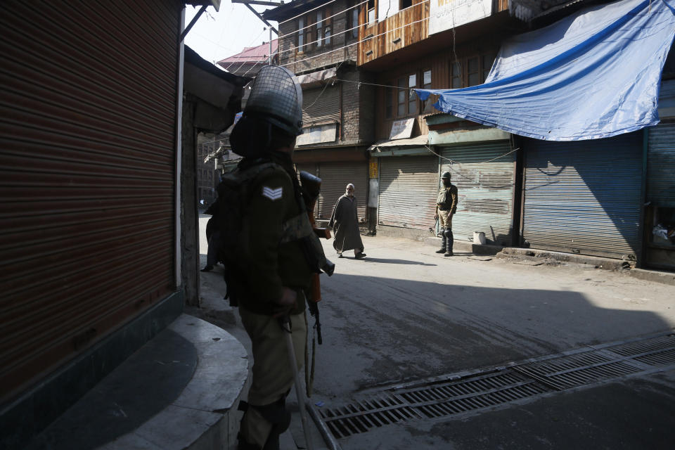 An elderly Kashmiri man walks past Indian paramilitary soldiers in Srinagar, Indian controlled Kashmir,Monday, Oct. 22, 2018. Armed soldiers and police have fanned out across much of Indian-controlled Kashmir as separatists challenging Indian rule called for a general strike to mourn the deaths of civilians and armed rebels during confrontation with government forces. (AP Photo/Mukhtar Khan)