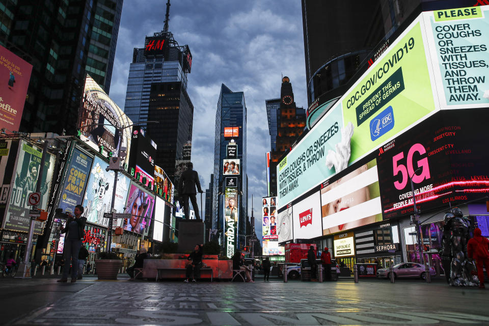 FILE - This March 20, 2020 file photo, shows a screen displaying messages concerning COVID-19, right, in a sparsely populated Times Square in New York. COVID-19 has shaken theater fans and shuttered all New York City's venues, including Broadway, which grossed $1.8 billion last season and attracted a record 15 million people. How Broadway — one the city's jewels — will reopen is still not clear. (AP Photo/John Minchillo, File)