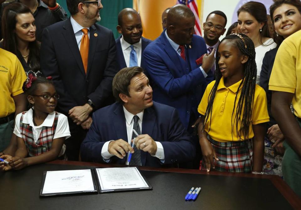 Gov. Ron DeSantis signs private-school voucher legislation flanked by students in Miami Gardens.