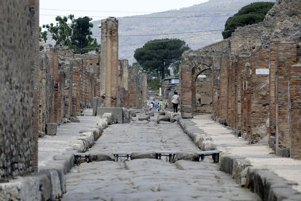 People visit the archaeological site of Pompeii, near Naples, southern Italy,Tuesday, May 26, 2020. Italy's archaeological site Pompeii has partly reopened to the public after shutting down for over two months amid lockdown measures to contain the spread of the new coronavirus. Mask wearing visitors were asked to queue in special circles to ensure social distancing, offered hand sanitizer and had their temperature checked before entering the site. (AP Photo/Alessandra Tarantino)