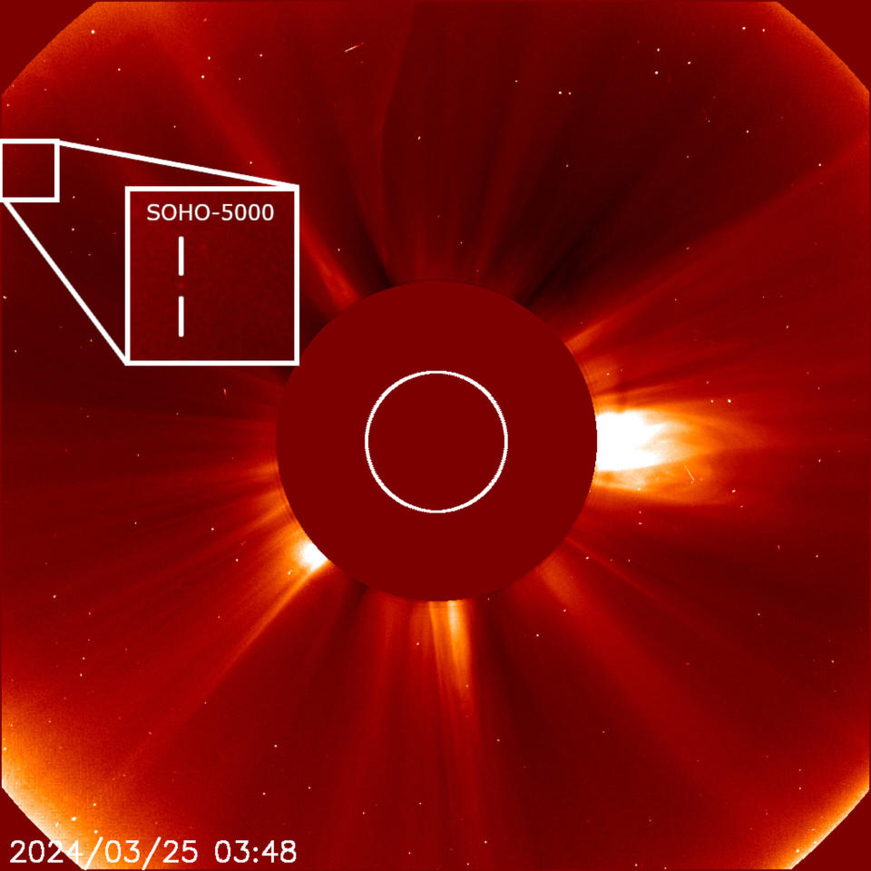 A bright orange circle covers almost the whole image, with a smaller disc in the middle. Out of the smaller disc protrude wisps of the Sun's atmosphere. To the upper right of the inner circle, an inset zooms in on a small square, with vertical lines surrounding a faint smudge. This is a full version of the header picture.