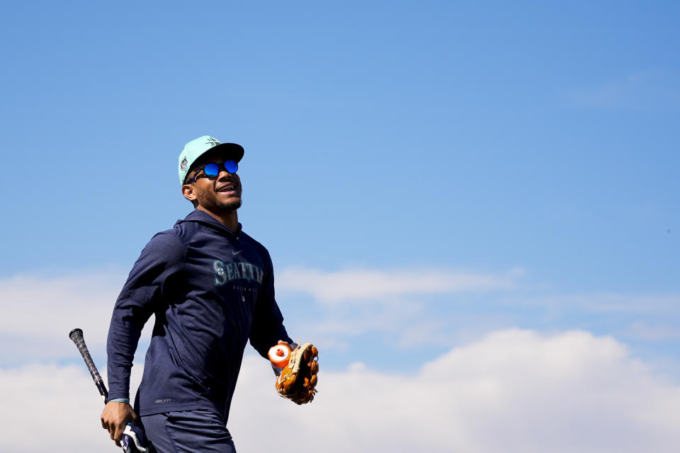 Seattle Mariners center fielder Julio Rodríguez runs off a practice field as fans yell for his autograph during spring training baseball workouts Thursday, Feb. 15, 2024, in Peoria, Ariz. (AP Photo/Lindsey Wasson)